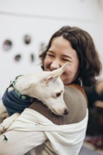 A smiling young woman tenderly holds a dog, capturing a moment of joy and companionship in a