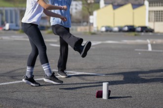 Friends dancing near a speaker and phone in a sunny parking lot. The casual outdoor scene captures
