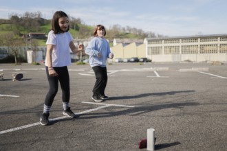 Two friends play a fun game outdoors in an empty parking lot under clear skies. They look engaged
