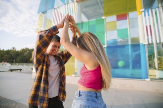 A happy lesbian couple dances joyfully in a vibrant outdoor setting, celebrating love and diversity
