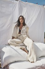 A young woman lounges on a rooftop, basking in the warmth of summer sun Dressed in light, flowing