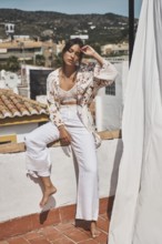 Young woman enjoying a sunny day on a rooftop, dressed in stylish bohemian attire The scenery