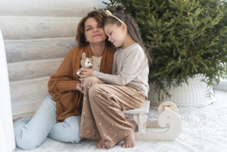 A heartwarming image showing a mother and daughter embracing beside a Christmas tree, capturing the