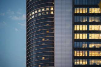 An urban skyscraper's windows glow warmly against the fading evening sky, capturing the essence of