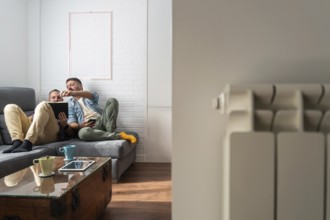 A gay couple enjoying a relaxing day at home, sitting on a comfortable sofa while engaging with
