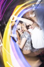 A vibrant party scene features a dynamic lesbian couple dancing energetically, surrounded by