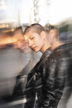 A lesbian woman with a buzz cut gazes confidently, wearing a black leather jacket, captured with