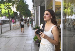 A young woman stands on a bustling city street, holding a camera Surrounded by passersby, she