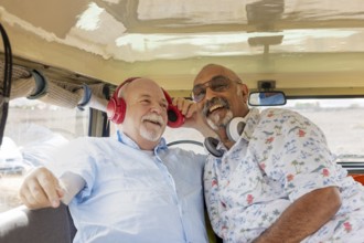 A senior gay couple smiles joyfully inside an off-road vehicle during a camping adventure. One man,