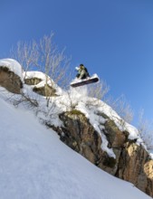 A daring snowboarder leaps off a snowy cliff, showcasing thrilling winter sports skills against a