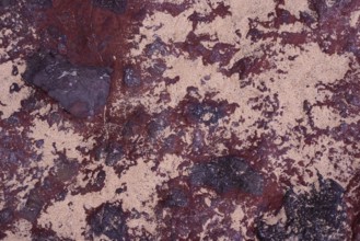 Close-up of the intricate textures of volcanic rocks surrounded by scattered sand at La Pared,