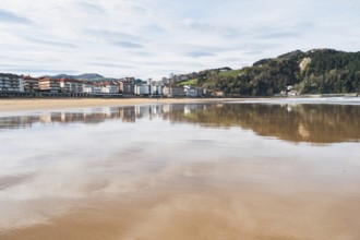 A serene image capturing a coastal town's reflection on a calm bay under a clear sky, showcasing