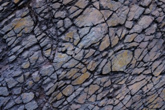 Detailed view of a jagged rock surface with interlocked gray and rust-colored stones in Mujeres