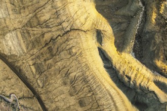 Aerial view of unique golden sandstone patterns in Utah's desert. Rugged terrain, sunlit textures,