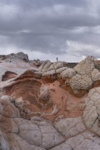 Unrecognizable person standing on the surreal, textured rock formations of White Pocket, Arizona,