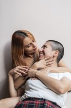 A lesbian couple enjoys a tender embrace, sharing smiles and happiness. Their affectionate