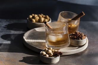 Spiced cognac-based cocktails garnished with cinnamon sticks and star anise, accompanied by