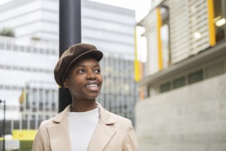 A confident black woman stands outdoors in an urban setting, wearing a stylish outfit The modern