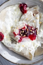 Traditional Ukrainian varenyky filled with cherry, topped with sour cream and sprinkled with