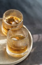 Two glasses of spiced cognac cocktail with cinnamon and star anise, accompanied by assorted nuts,