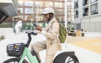 Black woman in a modern urban setting, riding a bicycle and checking her phone Dressed in a light