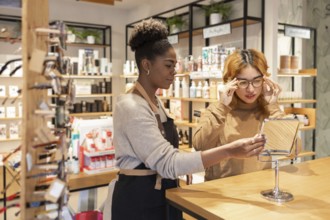 A worker in a cosmetics store helps a customer choose products. They stand by a counter filled with