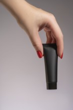 Cropped unrecognizable close-up of a female hand with red manicure elegantly holding a sleek black