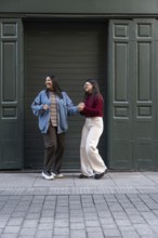 A cheerful latin lesbian couple, wearing casual outfits, holds hands while enjoying a fun moment