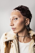 Wide angle close-up of a woman with a bold hairstyle, glamorous nose and ear piercings, striking