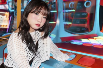 An Asian Gen Z girl enjoys an arcade game, surrounded by colorful lights Her expression and fashion