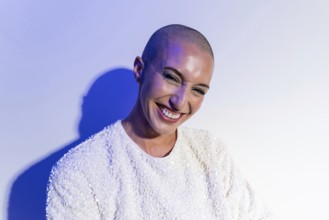 A middle-aged woman with a shaved head smiles confidently, reflecting self-assurance and