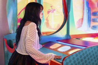 Young Asian Gen Z girl immersed in a vibrant arcade, enjoying the colorful lights and interactive