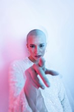 A middle-aged woman with a shaved head exudes confidence and style. She is pointing directly at the