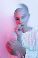 A striking image of a middle-aged woman with a shaved head, captured in a soft pink and blue light.