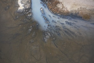A detailed aerial shot of a lagoon in Toledo, Spain, displaying muddy textures and branching water