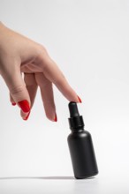 Cropped unrecognizable female hand with vibrant red manicure gracefully touching a sleek black