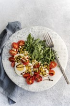 A vibrant keto salad featuring boiled eggs, rocket, cherry tomatoes, green peas, and sprouted