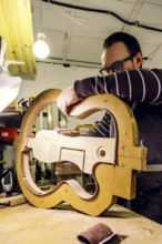 A skilled luthier at work in a workshop, carefully crafting a bass guitar using specialized tools