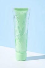 Transparent green tube filled with aloe vera infused cosmetic gel showcased against a light blue