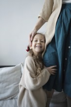 A young girl smiles while hugging her mother, showcasing a sense of warmth and security The scene