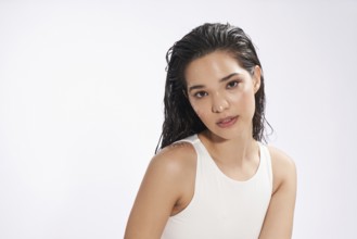 A young woman with wet hair and water droplets on her skin poses in a studio, looking directly at
