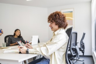 A team of coworkers collaborating in a bright, modern office One person is focused on a tablet,