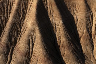 Aerial view of a rugged desert landscape showcasing intricate erosion patterns and ridges in brown