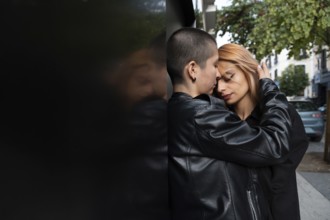 A loving lesbian couple shares an intimate, tender moment while standing closely against a wall in