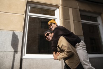 A happy gay couple in stylish attire celebrates love on a sunny day. The urban backdrop highlights