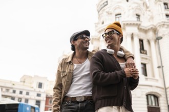 A joyful colombian gay couple enjoying a casual city walk. Both are wearing sunglasses and