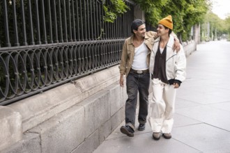 A Colombian gay couple enjoys a romantic walk, embracing each other in a casual urban setting. The