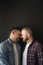 A happy gay couple shares a tender moment, leaning forehead to forehead. Their connection is