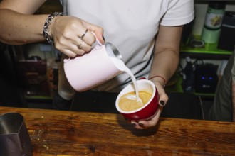 A barista skillfully pours milk into espresso to create latte art, highlighting the process of