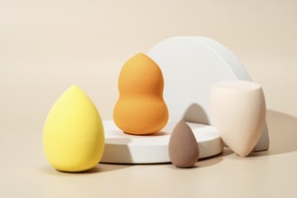 A variety of colorful cosmetic sponges in different shapes and sizes on a light background,